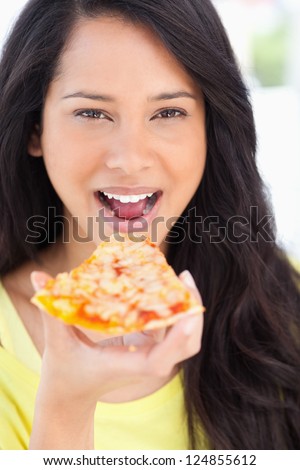 A close up shot of a woman about to eat pizza as she looks at the camera