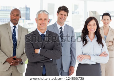 Smiling and confident business team standing in front of a bright window