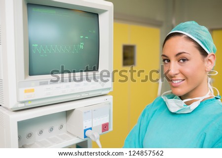Smiling surgeon standing next to a monitor in a surgery room