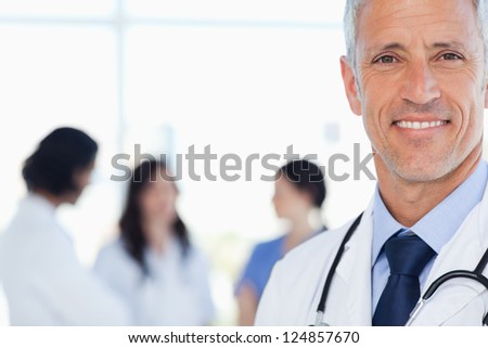 Doctor showing a beaming smile with his medical interns behind him