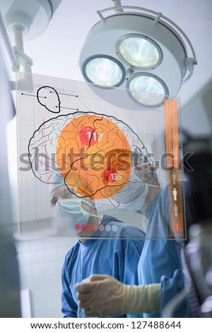 Two surgeons looking at the brain on an interface in surgery