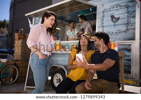 Friends looking at mobile phone and smiling in food truck van