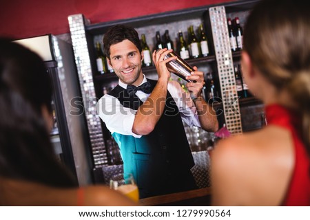 Bartender shaking cocktail in cocktail shaker at bar counter in nightclub