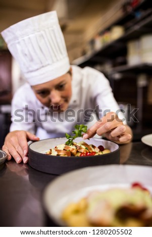 Female chef garnishing delicious desserts in a plate at hotel