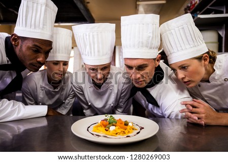 Group of chefs looking at prepared pasta in kitchen at home