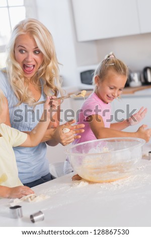 Mother making a face while her children take care of the dough to eggs