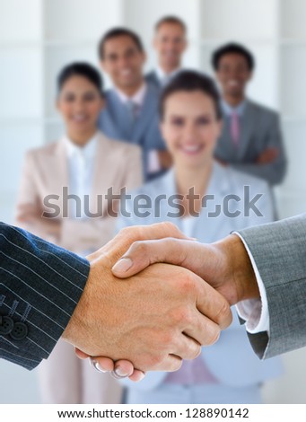 Businessmen shaking hands with smiling business team behind them