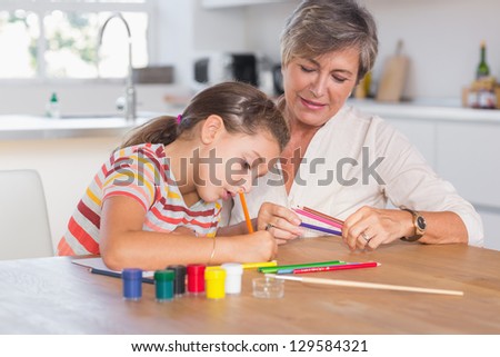 Child drawing with her grandmother in kitchen