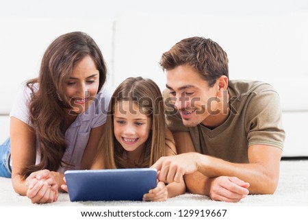 Family lying on a carpet with tablet in the living room
