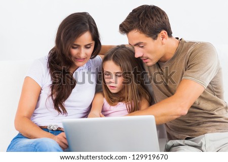 Family sitting on a sofa with the laptop in the living room