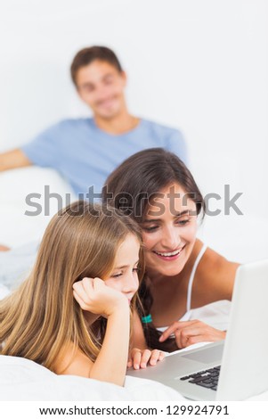 Happy family sitting with a laptop on the bed