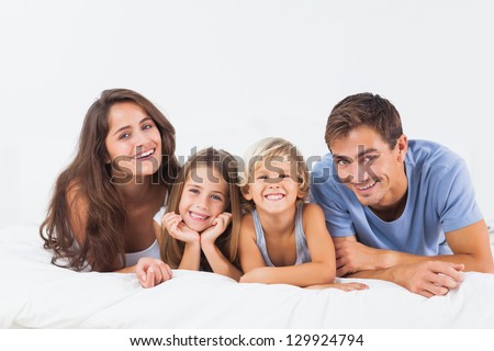 Happy Family Lying On A Bed Together In The Bedroom