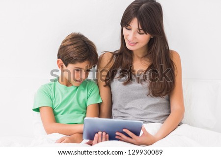 Mother and son using tablet pc in bed