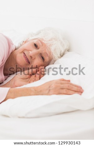 Elderly woman waking up in bed