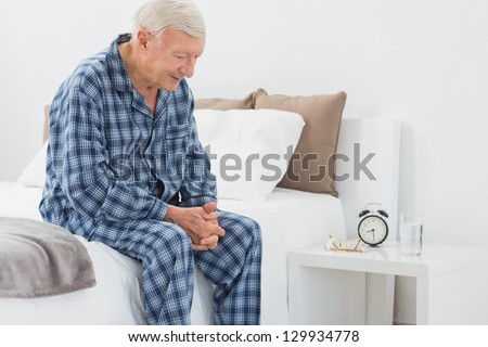 Elderly man sitting on the bed in the bedroom