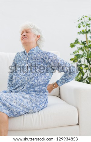 Elderly woman with back pain  in the living room