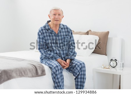 Elderly man sitting on his bed in the bedroom