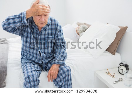 Elderly man suffering with head pain in the bedroom