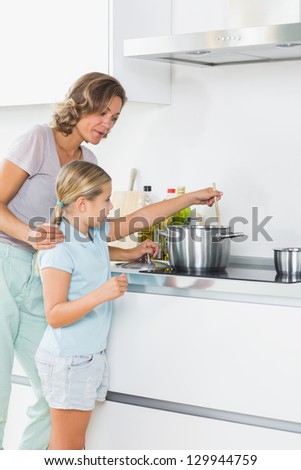 Mother teaching daughter how to cook at home