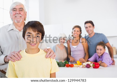 Grandfather and grandson standing beside the kitchen counter with family behind them