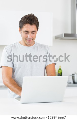 Happy man with laptop in kitchen
