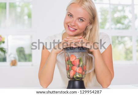 Smiling woman putting hands on the mixer in the kitchen