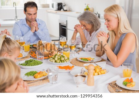 Family praying before thanksgiving dinner