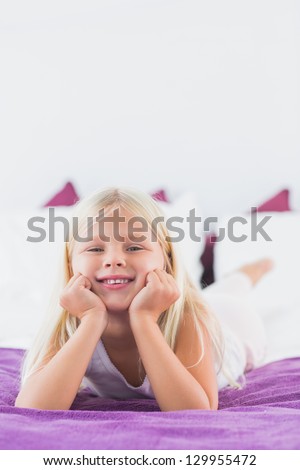 Little girl lying on a double bed in the bedroom