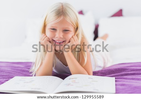 Little girl reading her lesson on the bed