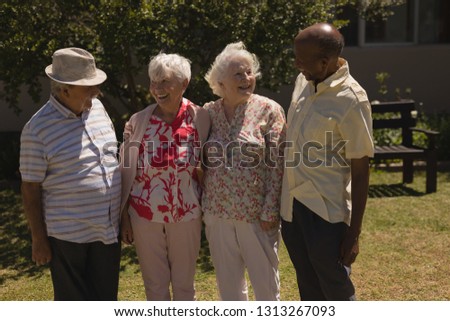 Front view of happy senior friends interacting with each other in garden
