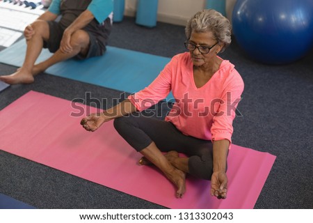 High angle view of active senior woman doing yoga in yoga position in fitness studio