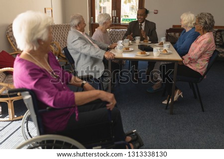 Disabled senior woman with happy group of senior friends having fun at nursing home