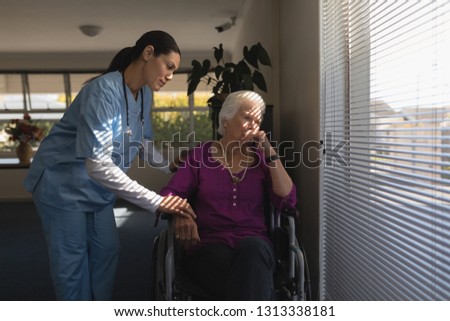 Front view of female doctor consoling sad disabled senior woman at nursing home