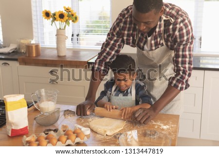 Front view of African American father and son rolling out cookie dough in kitchen at home