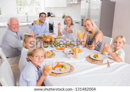 Family raising their glasses at thanksgiving and looking at camera
