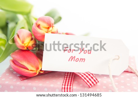 Bouquet of tulips next to a gift with a card for a mother close up