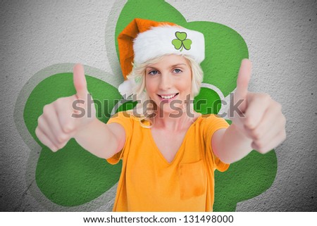 Girl in orange t-shirt giving thumbs up on wall style shamrock background