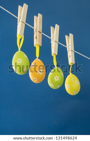Easter eggs hanging from a washing line on blue background