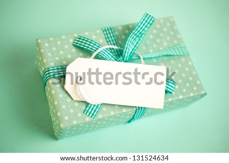 Green gift wrapped box with blank tag on green background