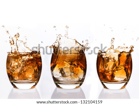 Serial arrangement of whiskey splashing in tumbler on white background