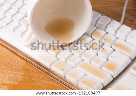 Cup of tea spilled out over a keyboard close up on a desk