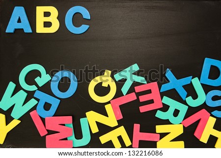 Alphabet magnets in a jumble on blackboard with Abc in order at the top