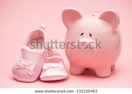 Pink booties and piggy bank on pink background