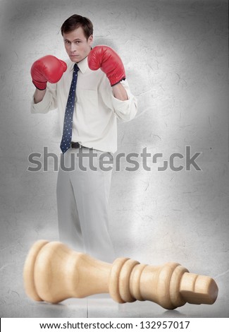 Businessman in red boxing gloves with knocked over white chess piece