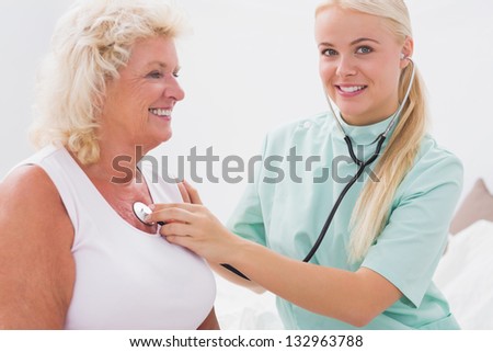 Home nurse examining a smiling aged woman at home