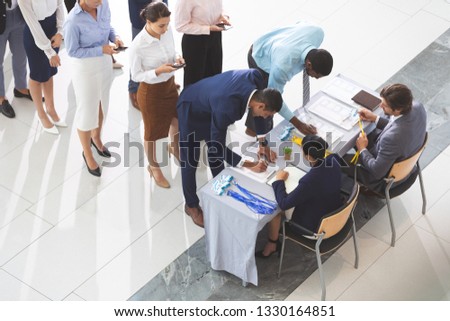High angle view of diverse business people checking in at conference registration table in office lobby