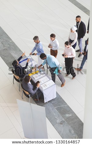 High angle view of diverse business people checking in at conference registration table in lobby