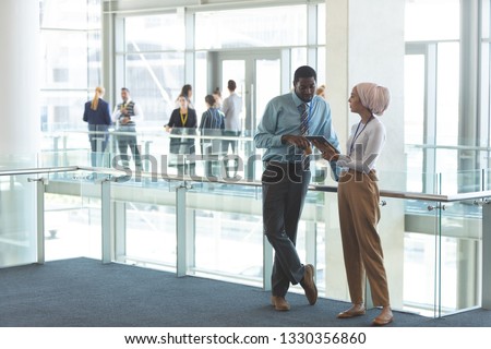 Front view of young diverse business executives discussing over digital tablet in office lobby