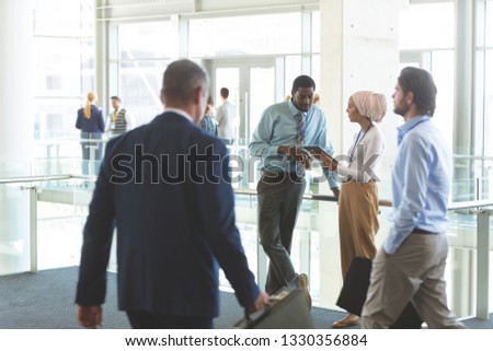 Front view of young diverse business executives discussing over digital tablet in office