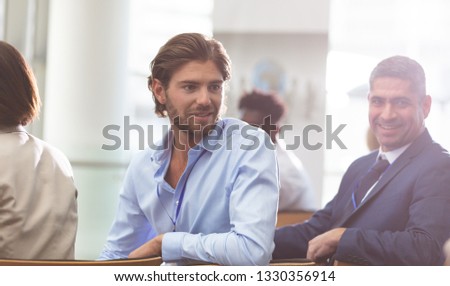Front view close up of Caucasian businessman attending a business seminar while he speaks with coworkers in office building